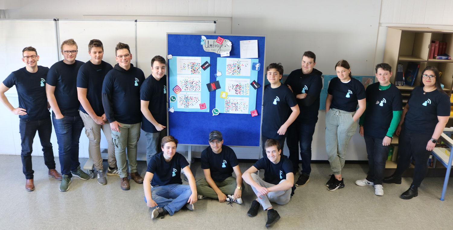 Die Social Media Scouts (mit Lehrer Andreas Bork (links) und Schulsozialteam-Mitarbeiterin Alina Pack (rechts) präsentieren die Ergebnisse ihrer Umfrage in ihren neuen T-Shirts 